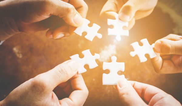 Hand of diverse people connecting jigsaw puzzle. Concept of partnership and teamwork in business